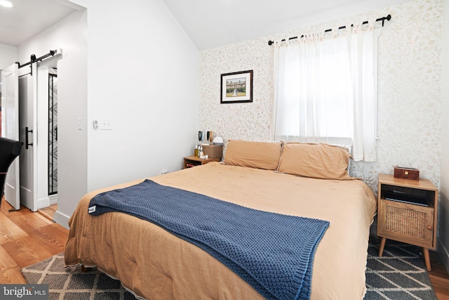 307 Kendall Blvd, Oaklyn, NJ 08107 - bedroom with a barn door, vaulted ceiling, wallpapered walls, and wood finished floors