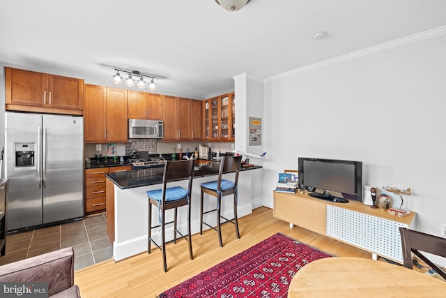 3024 Wisconsin Ave NW Unit 208, Washington, DC 20016 - kitchen with appliances with stainless steel finishes, a breakfast bar area, ornamental molding, glass insert cabinets, and brown cabinetry