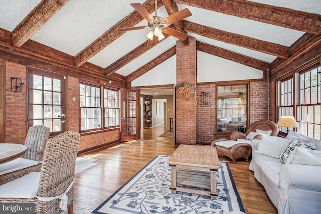 living room featuring brick wall, a textured ceiling, a ceiling fan, and wood finished floors
