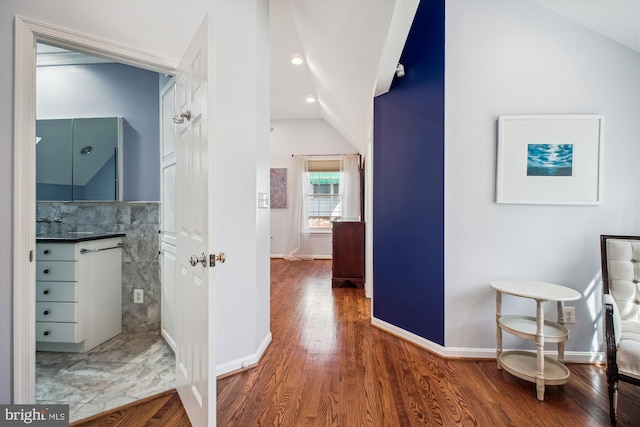 hall featuring baseboards, recessed lighting, vaulted ceiling, and wood finished floors
