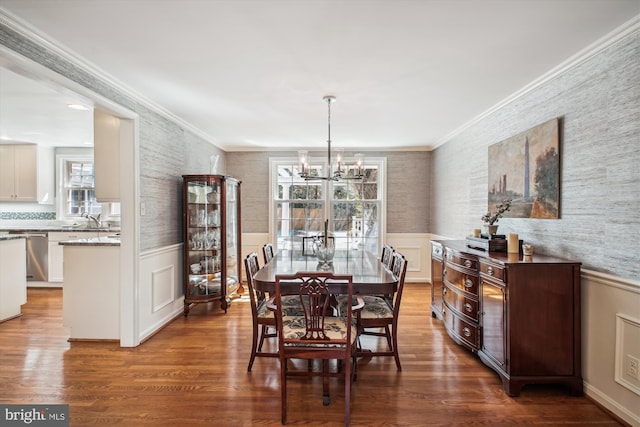 dining space featuring wallpapered walls, wood finished floors, a notable chandelier, and wainscoting