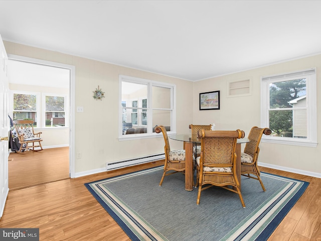 dining space featuring light wood-style floors, baseboard heating, and baseboards