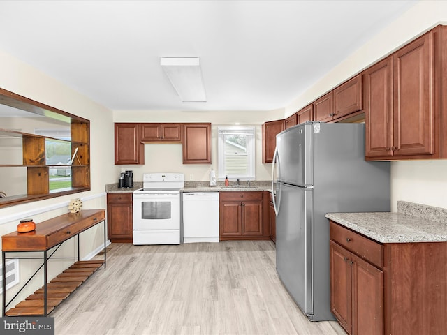 kitchen featuring a healthy amount of sunlight, light wood finished floors, a sink, and white appliances