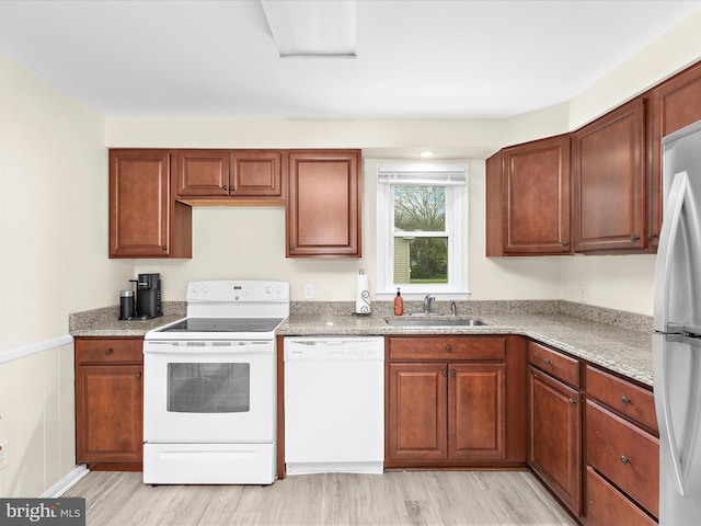 kitchen featuring white appliances, light wood-type flooring, a sink, and light stone counters