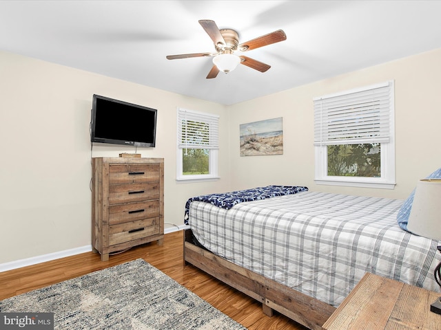 bedroom featuring ceiling fan, baseboards, and wood finished floors