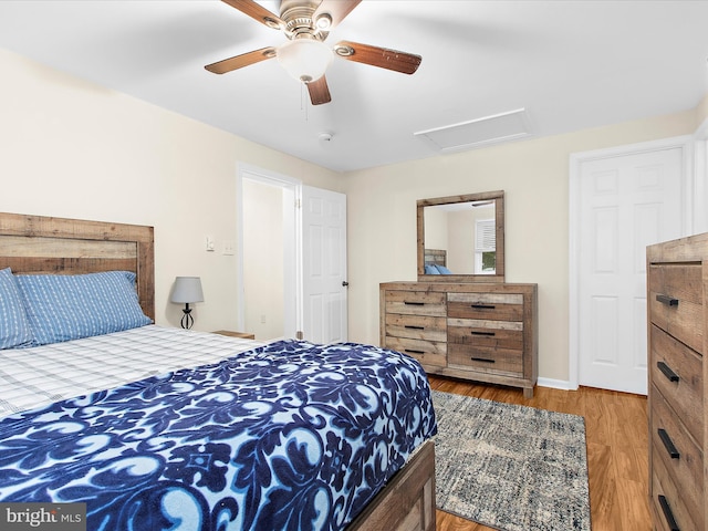 bedroom featuring wood finished floors, attic access, baseboards, and a ceiling fan