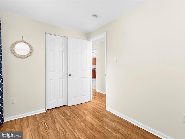 unfurnished bedroom featuring a closet, baseboards, and wood finished floors