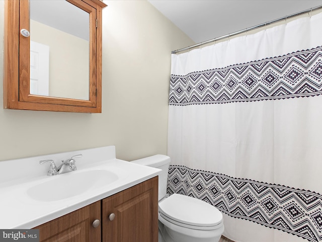 bathroom featuring toilet, vanity, and a shower with curtain