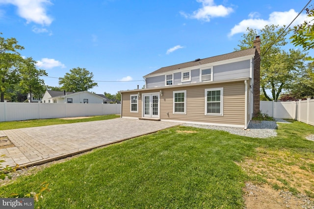 rear view of property with a fenced backyard, french doors, a chimney, a patio area, and a yard