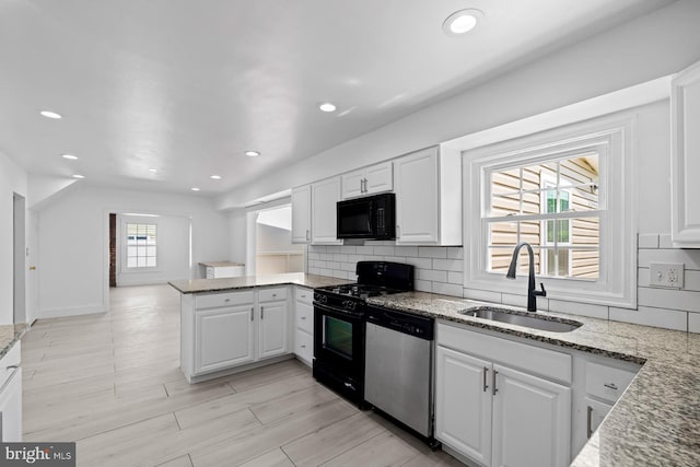 kitchen with a peninsula, white cabinetry, a sink, and black appliances