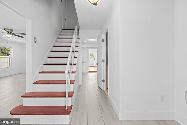 stairs with baseboards, a ceiling fan, wood finished floors, and a wealth of natural light