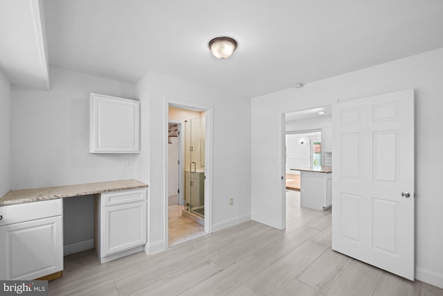 unfurnished office featuring light wood-type flooring and baseboards