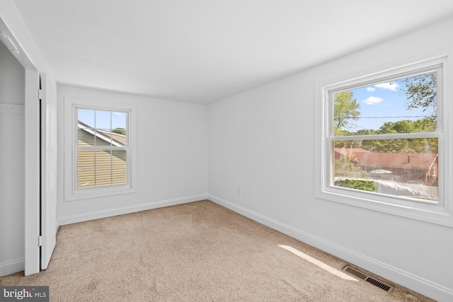 interior space featuring visible vents, carpet, baseboards, and multiple windows