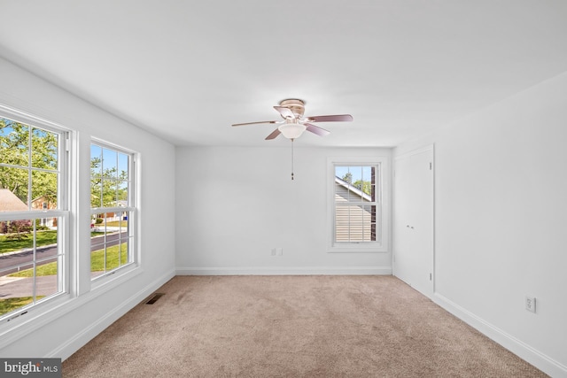 carpeted spare room featuring visible vents, baseboards, and ceiling fan