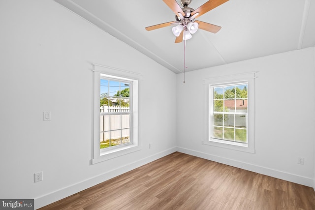 spare room featuring baseboards, lofted ceiling, a healthy amount of sunlight, and wood finished floors