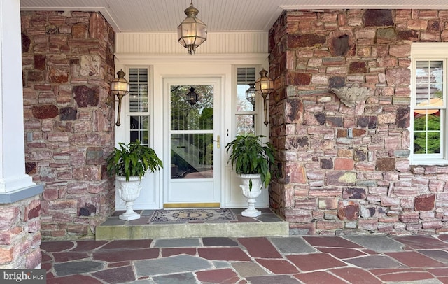 doorway to property with stone siding and covered porch