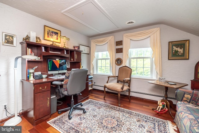 office with attic access, wood finished floors, lofted ceiling, a baseboard heating unit, and a textured ceiling