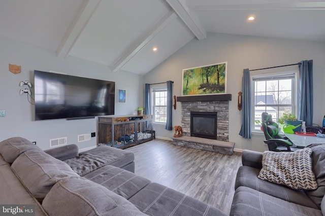 living room with baseboards, visible vents, a stone fireplace, vaulted ceiling with beams, and wood finished floors