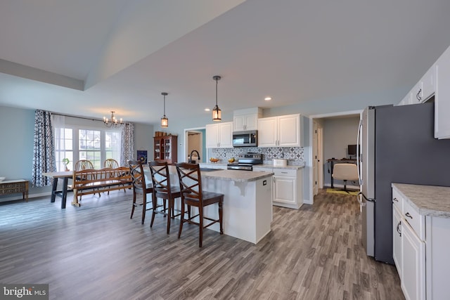 kitchen featuring light countertops, a kitchen bar, stainless steel appliances, decorative backsplash, and white cabinets