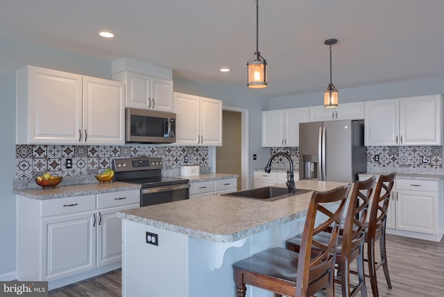 kitchen with white cabinetry, light countertops, tasteful backsplash, a sink, and appliances with stainless steel finishes