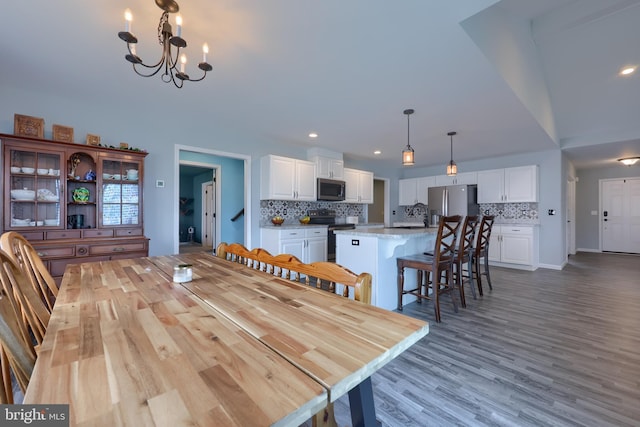 dining area with wood finished floors, an inviting chandelier, and recessed lighting