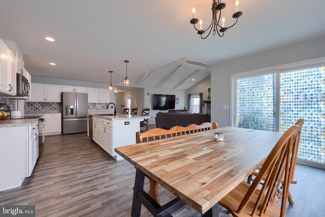 dining space featuring dark wood-style floors, vaulted ceiling, recessed lighting, and an inviting chandelier