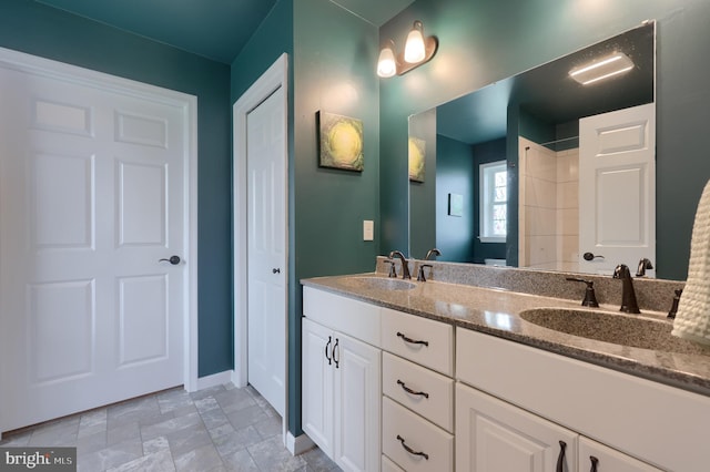 full bathroom with baseboards, double vanity, a sink, and stone finish flooring