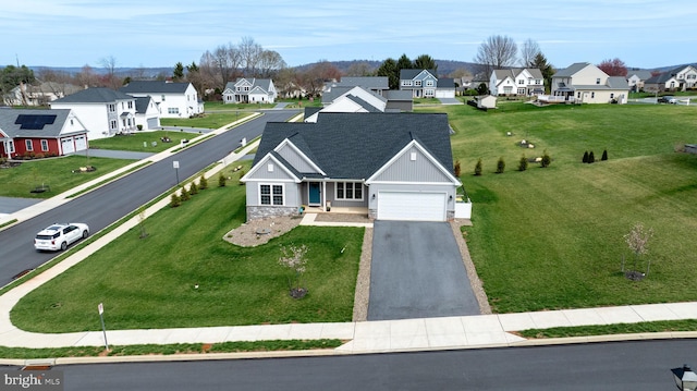 view of front of house featuring stone siding, an attached garage, roof with shingles, a residential view, and driveway
