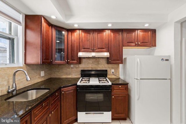 2225 S Hicks St, Philadelphia, PA 19145 - kitchen featuring dark stone counters, under cabinet range hood, a sink, gas range, and freestanding refrigerator