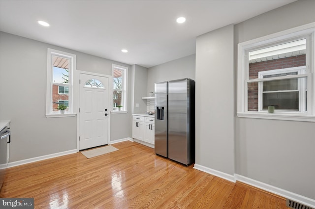 kitchen with baseboards, light wood-style flooring, light countertops, visible vents, and stainless steel appliances