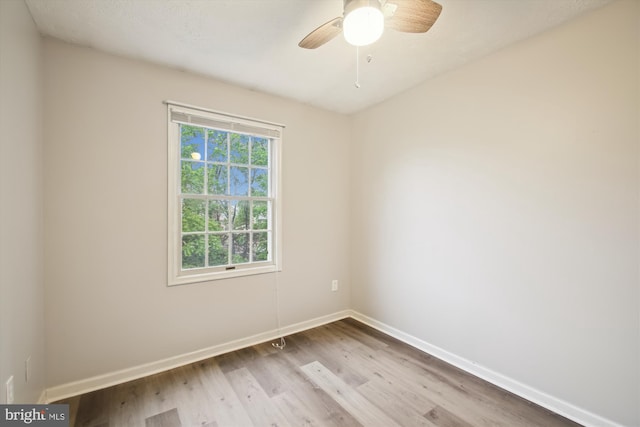 empty room featuring wood finished floors, baseboards, and a ceiling fan
