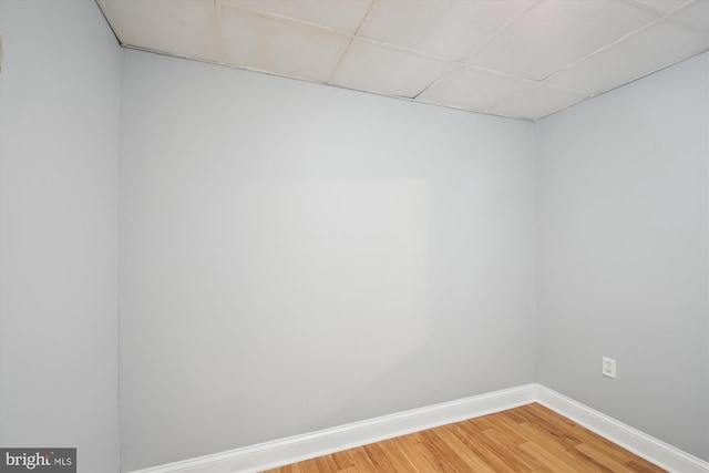 empty room featuring light wood finished floors, baseboards, and a paneled ceiling