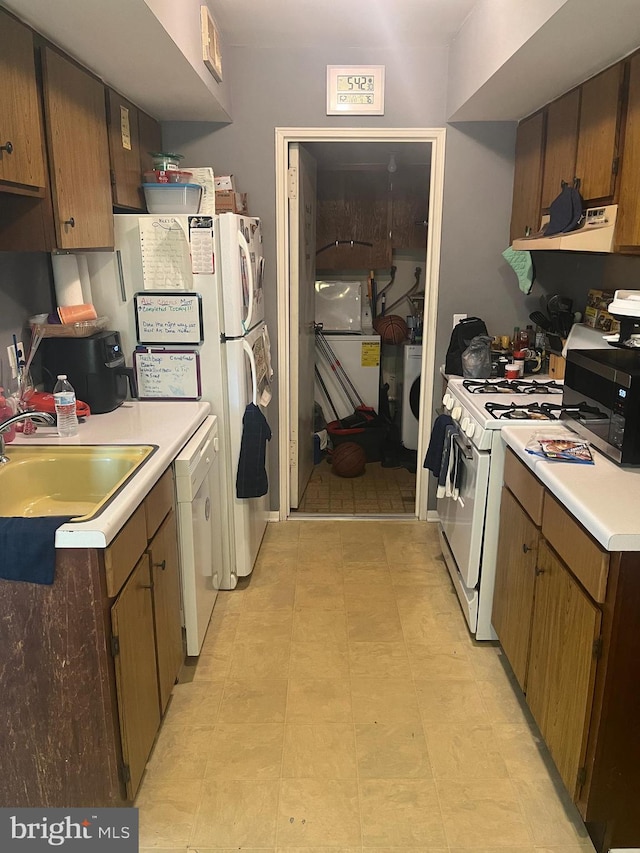 kitchen with ventilation hood, a sink, white appliances, light countertops, and washer / clothes dryer