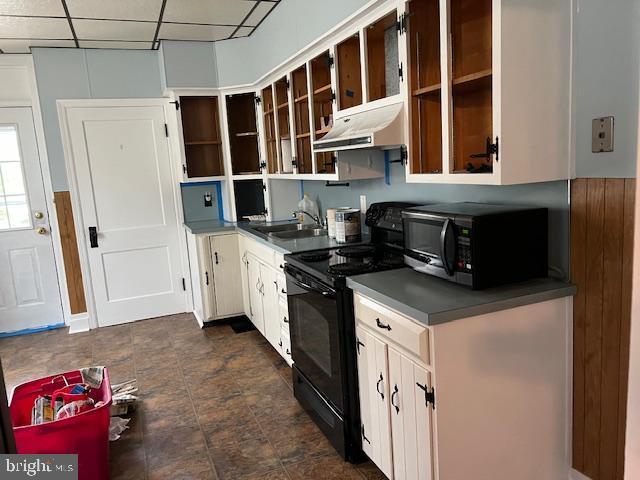 kitchen featuring open shelves, under cabinet range hood, dark countertops, a sink, and black range with electric stovetop