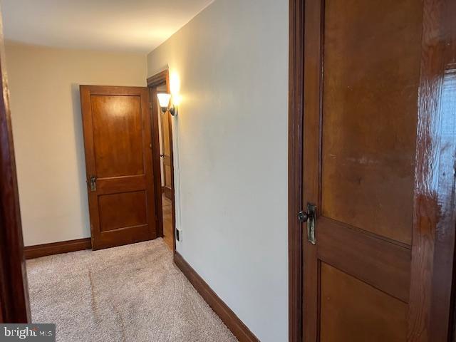 corridor featuring baseboards and light carpet