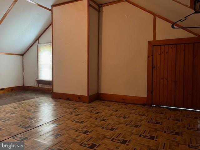 additional living space featuring baseboards and vaulted ceiling