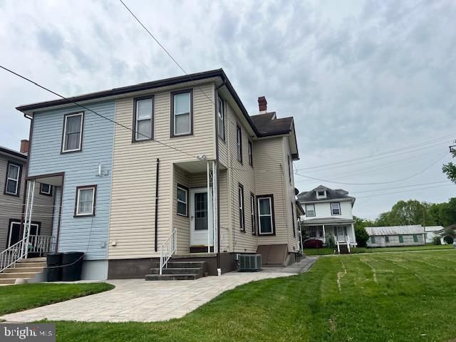 back of property featuring a lawn, a chimney, and central AC unit