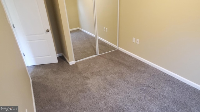 unfurnished bedroom featuring baseboards, carpet floors, and a closet