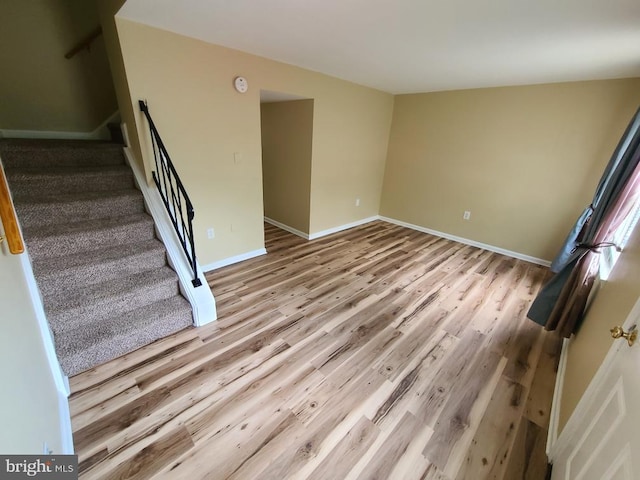 unfurnished living room with baseboards, wood finished floors, and stairs