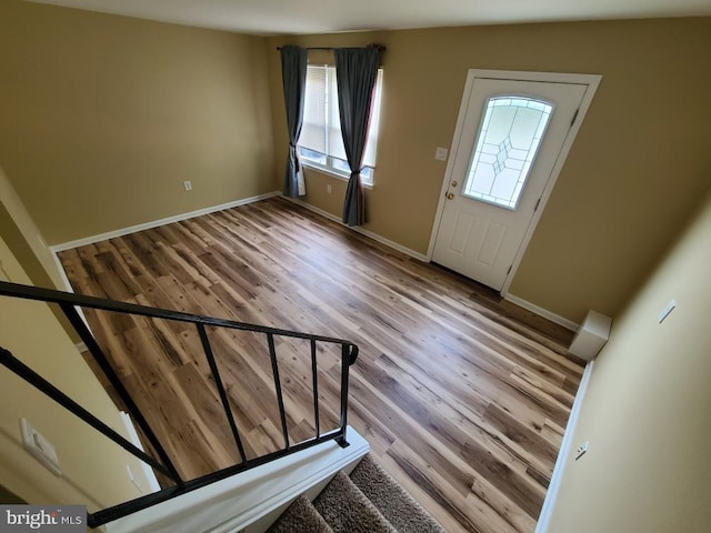 foyer entrance featuring stairway, baseboards, and wood finished floors
