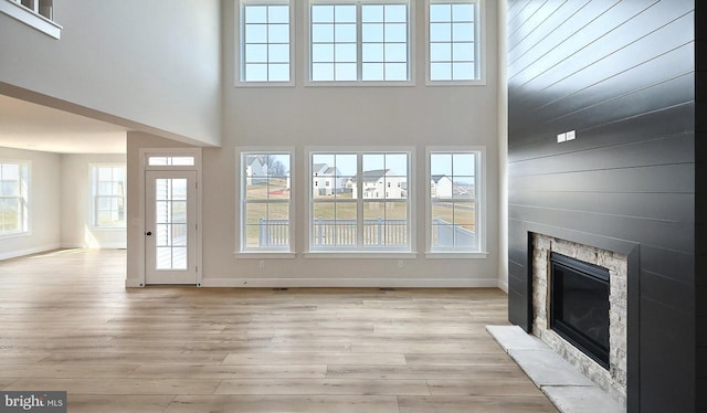 1999 N Fall Harvest Dr, Mechanicsburg, PA 17055 - unfurnished living room featuring baseboards, light wood finished floors, a towering ceiling, and a fireplace with flush hearth