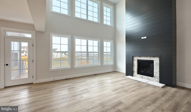 1999 N Fall Harvest Dr, Mechanicsburg, PA 17055 - unfurnished living room with light wood-style flooring, baseboards, a high ceiling, and a stone fireplace
