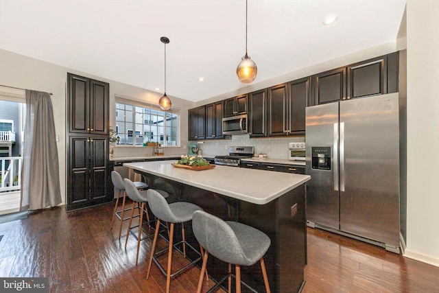 8473 Randell Ridge Rd, Frederick, MD 21704 - kitchen featuring appliances with stainless steel finishes, a kitchen island, light countertops, dark wood-type flooring, and a kitchen breakfast bar
