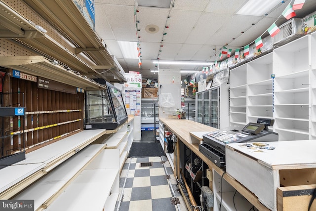 misc room featuring tile patterned floors, a drop ceiling, and a workshop area