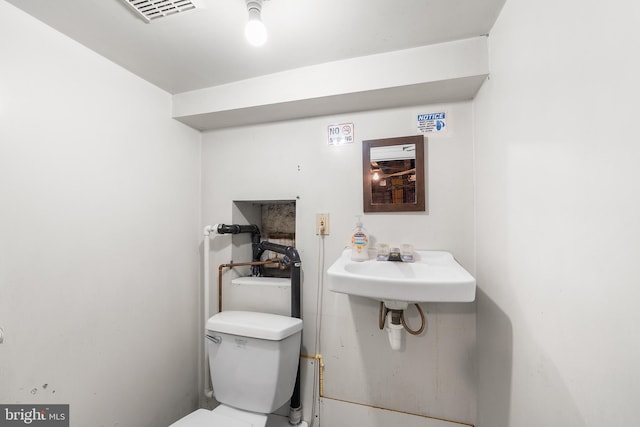 bathroom featuring toilet, a sink, and visible vents