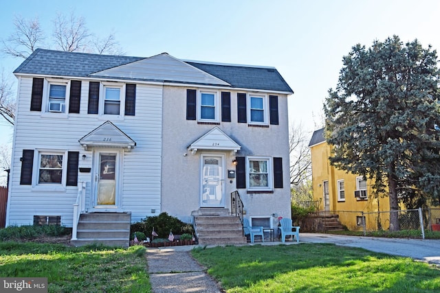 view of front of house with a shingled roof, fence, and a front lawn