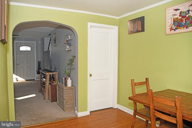 dining area with arched walkways, wood finished floors, baseboards, and ornamental molding