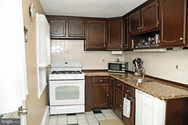kitchen with tasteful backsplash, a sink, white appliances, dark brown cabinetry, and dark stone counters