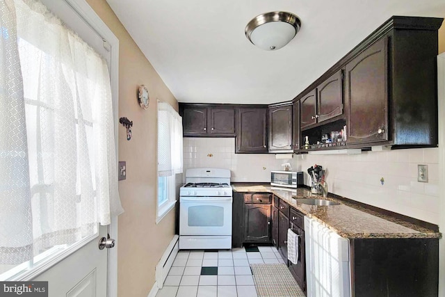 kitchen with stainless steel microwave, dark brown cabinetry, white range with gas cooktop, backsplash, and a sink
