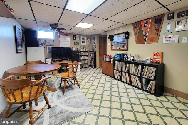 interior space featuring baseboards, a paneled ceiling, and light floors
